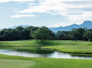 Lung Tan Golf Club fairway with a pond, trees and mountains behind